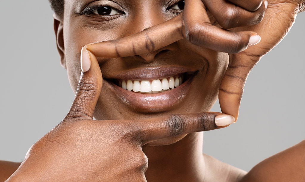 Beautiful black woman framing her healthy white teeth with fingers